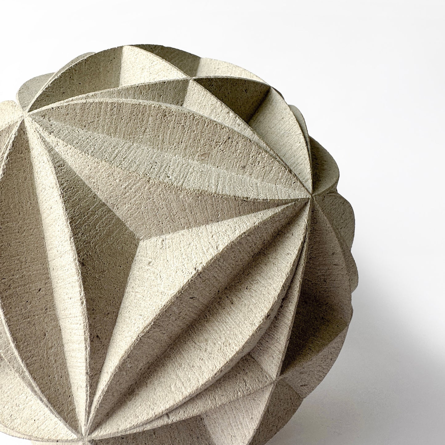 Buff coloured with bold geometric design carved out of it. behind is a white background