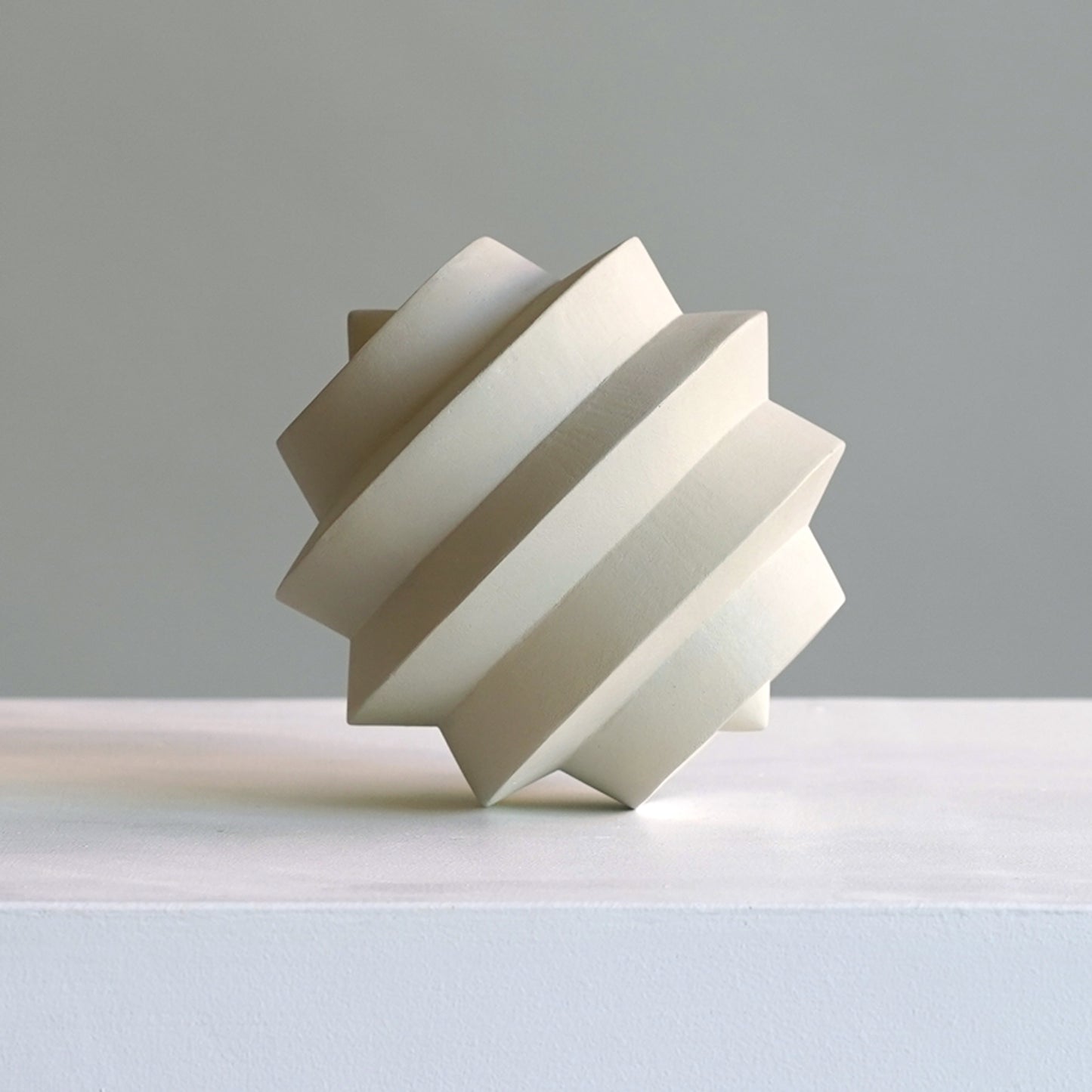 Modern geometric sculpture on a light grey background