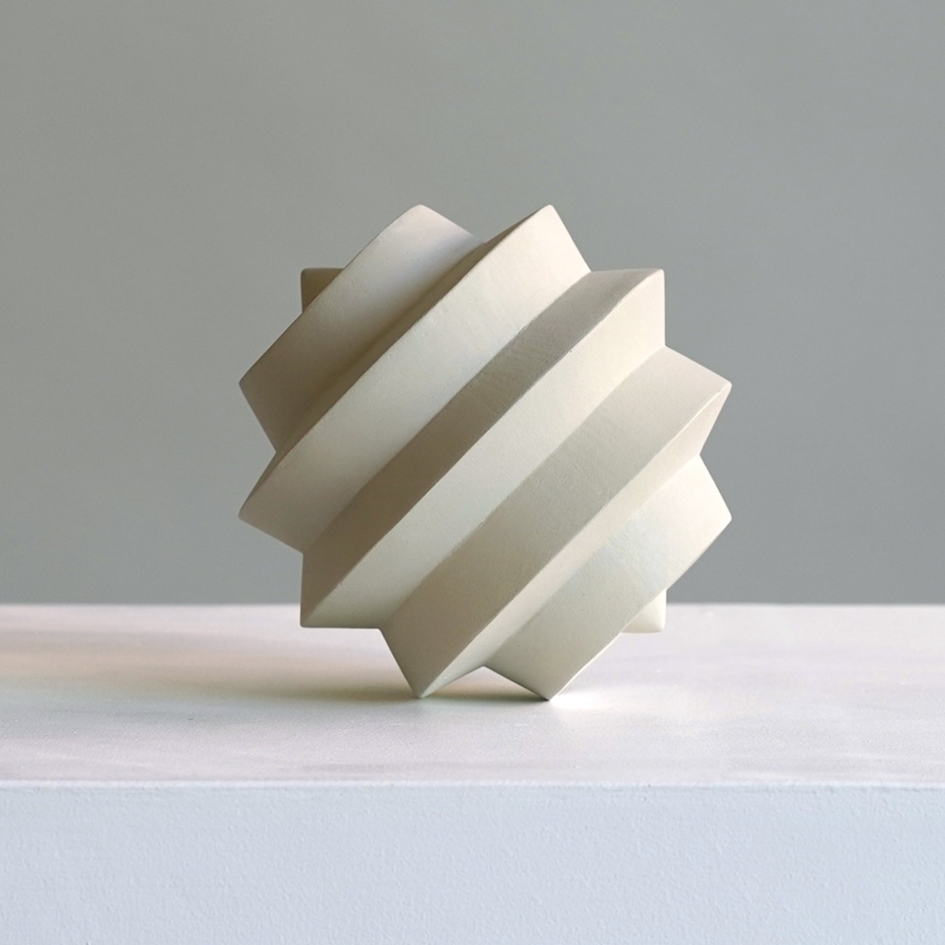 Modern geometric sculpture on a light grey background