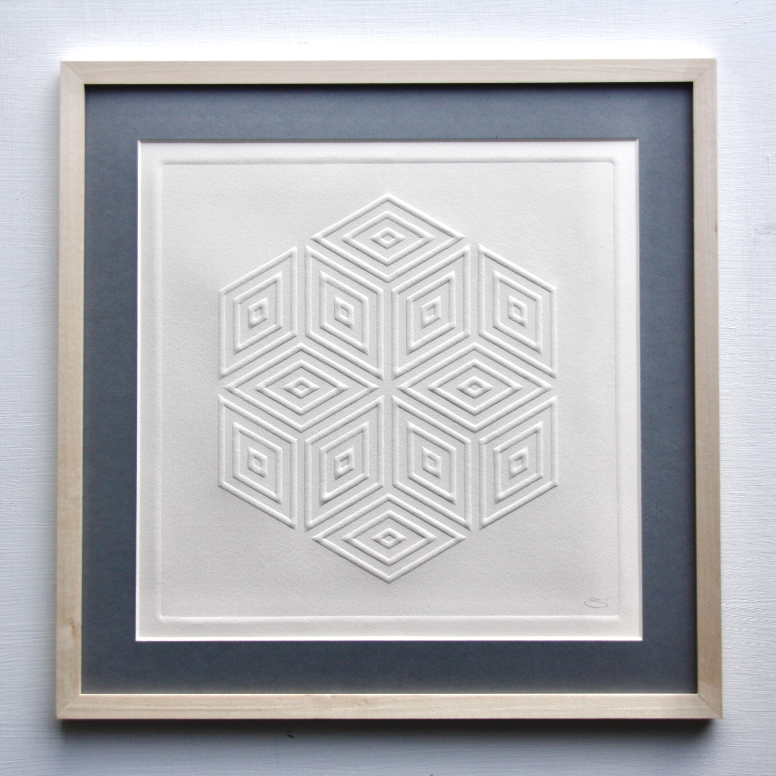 Paper pressed into the stone carving to make a raised embossing. Pattern is a geometric shape based on a diamond