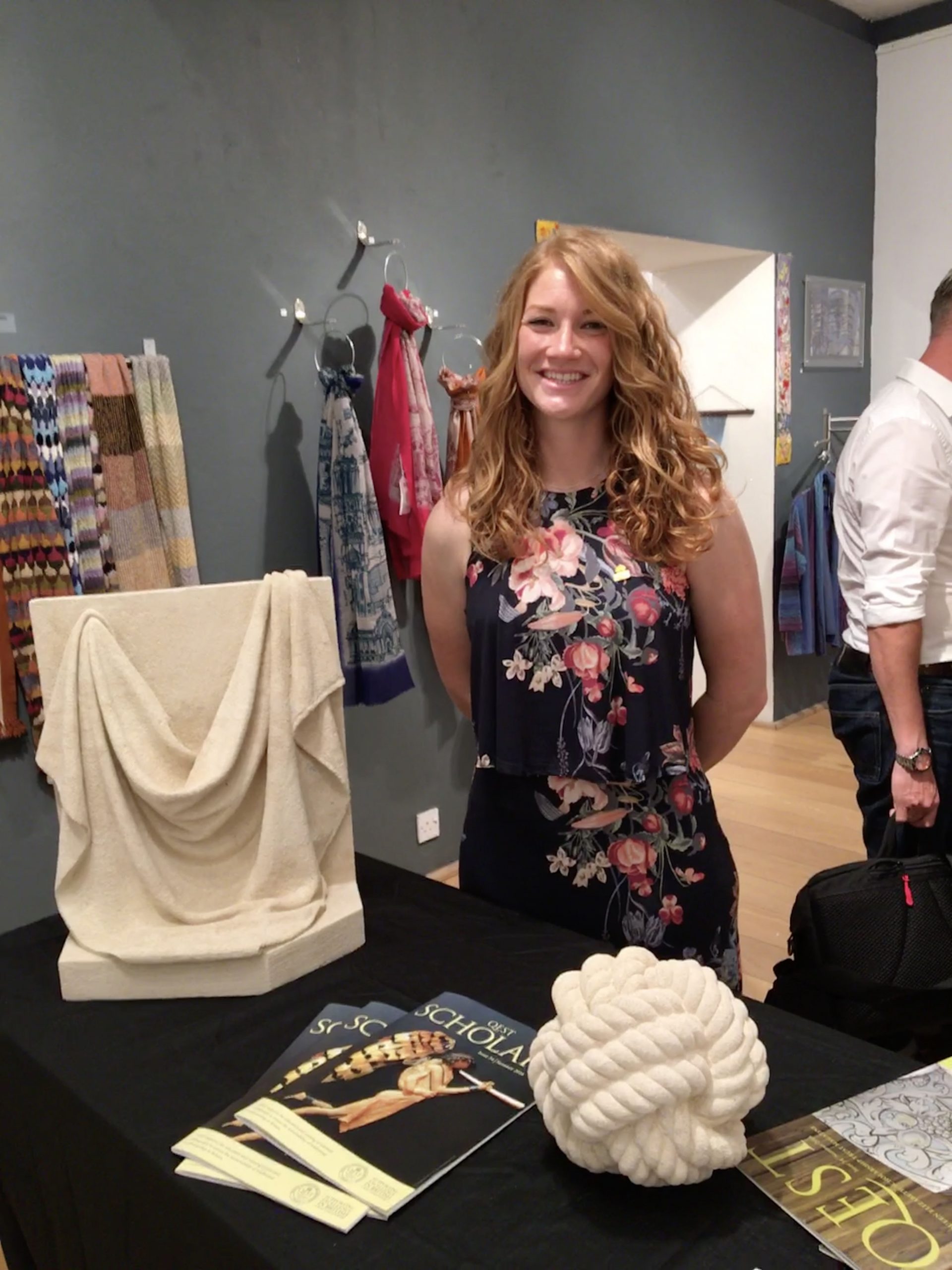 Zoe standing in front of her carvings at a Private view