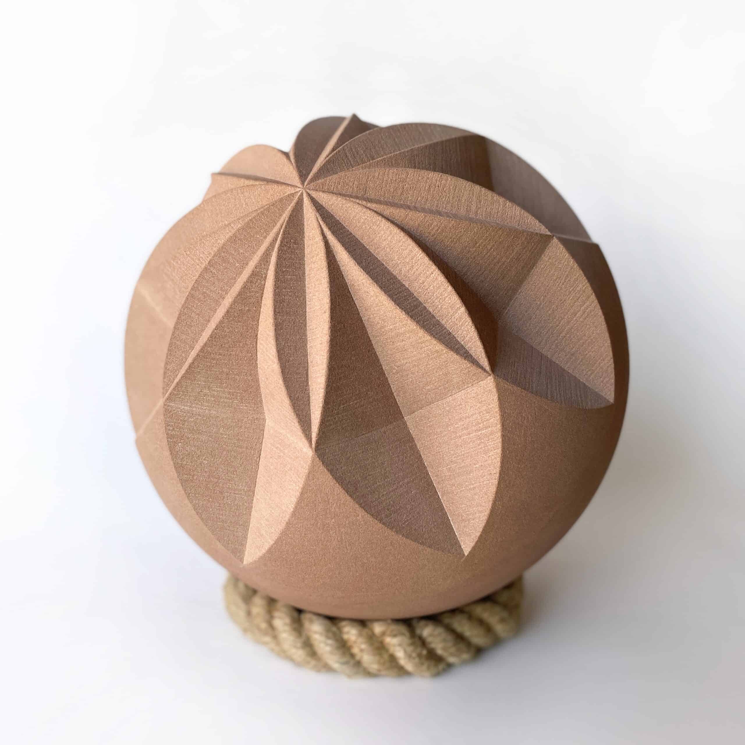 Red sandstone sphere carved with a geometric pattern