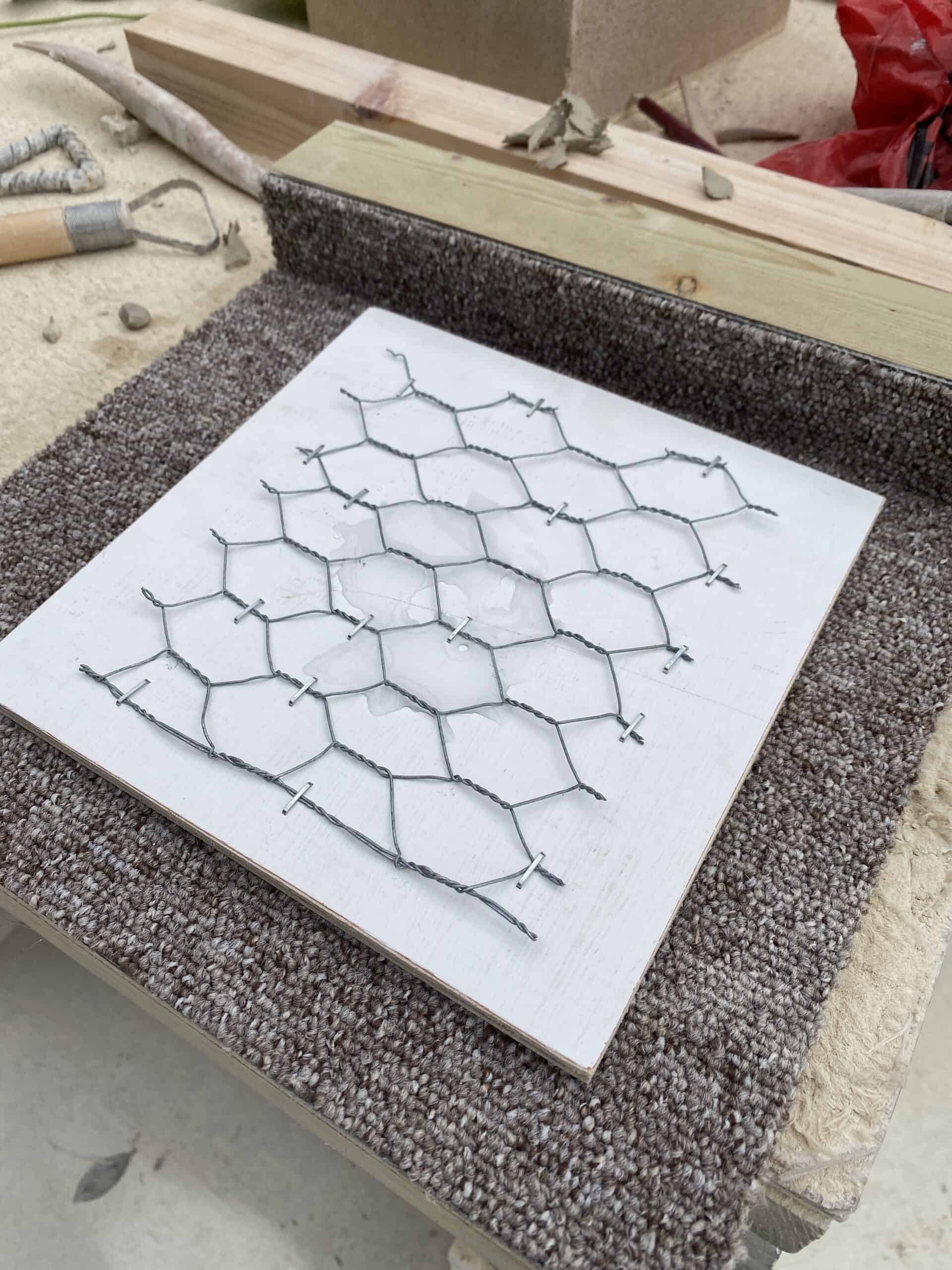 Chicken wire on a painted white piece of wood ready for the clay to go on top