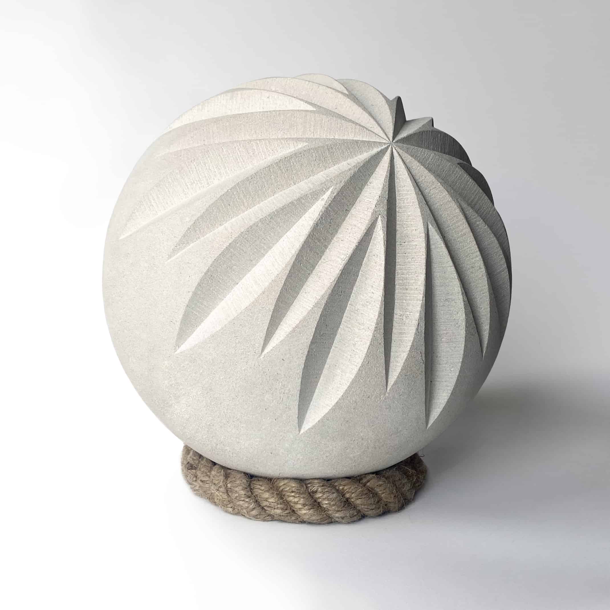 Buff coloured stone sphere with a geometric pattern carving into the stone