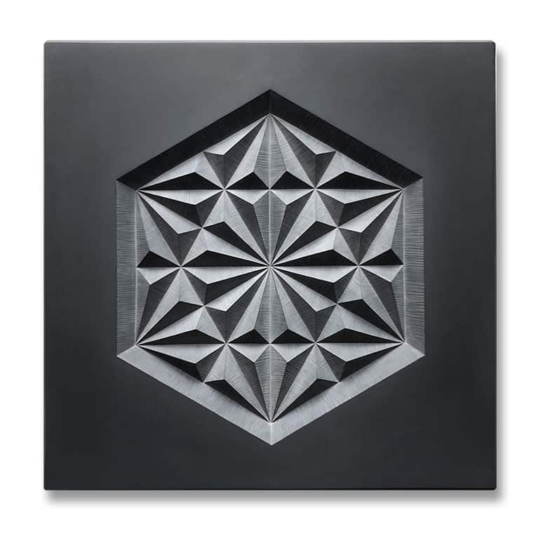 Angular geometric pattern carved into dark grey slate.