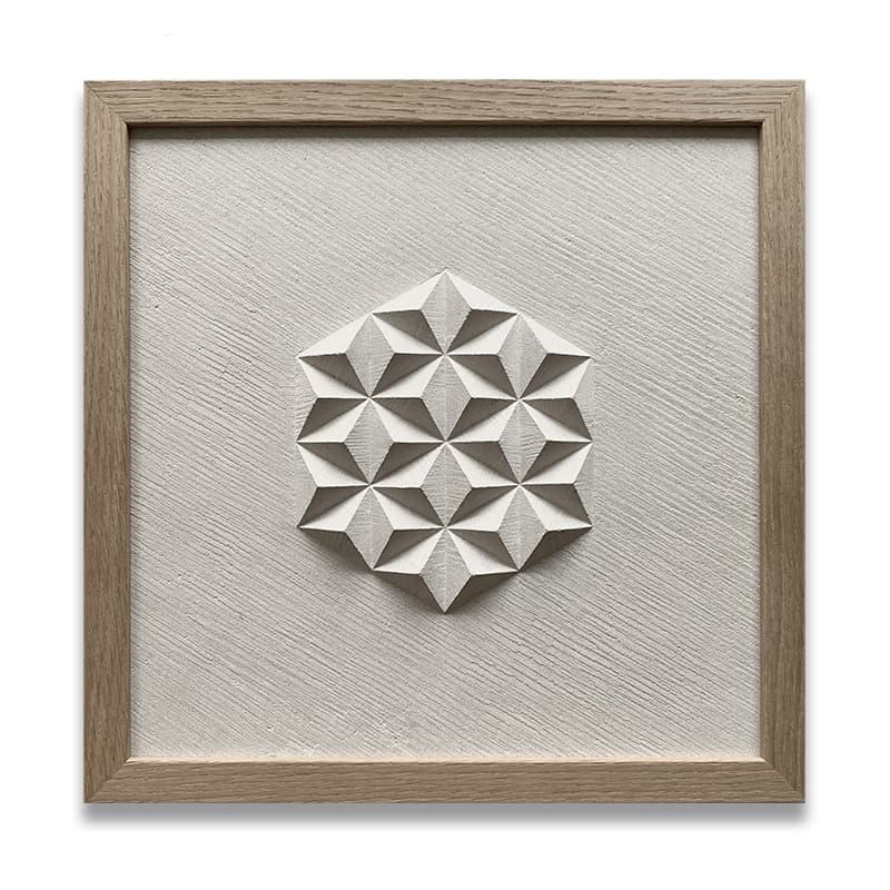 Hand carved geometric pattern which looks like pyramids, in a buff limestone framed with an oak